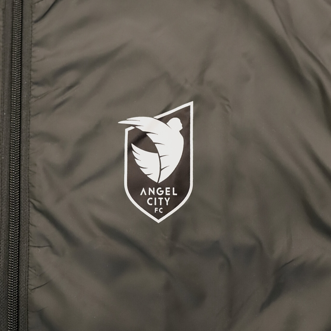Stay warm and look good in our Angel City FC Unisex Black and Sol Rosa Full Zip Wind Jacket.  The lightweight jacket features a hood, pops of Sol Rosa on the shoulders, a Sol Rosa Angel City FC crest on the left chest, front pockets, mesh lining, and adjustable cinches on the hips.  Pairs well with our Unisex Tonal Joggers.